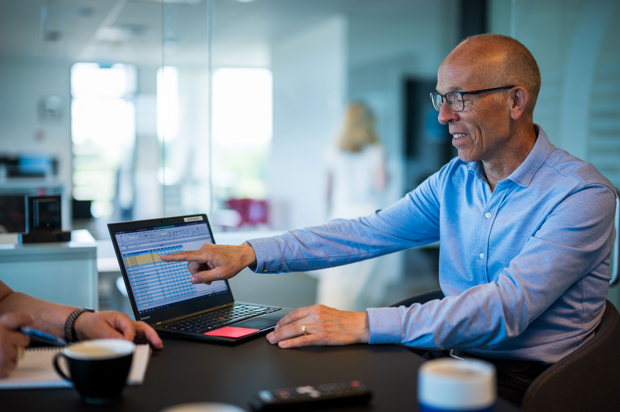 Menedżer kluczowych klientów Fibreline na spotkaniu, wskazując na swój komputer